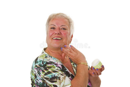 老年妇女在脸上涂乳液