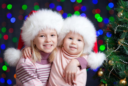 在明亮背景下戴圣诞老人帽的有趣的孩子们