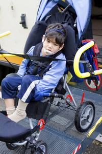 残疾小男孩坐在公共汽车轮椅升降机上