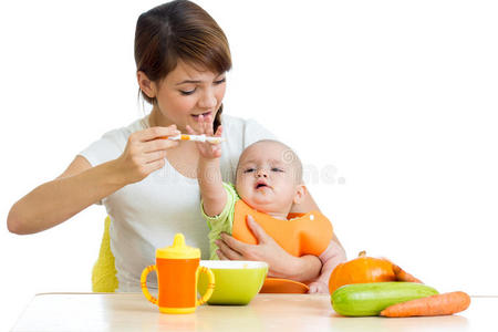 年轻的母亲用勺子喂她的女婴
