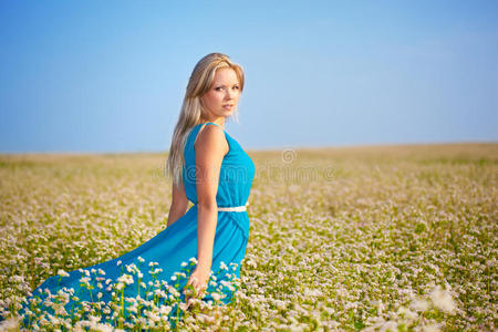 在田野上穿着蓝色连衣裙的漂亮女人