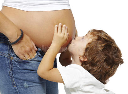 男孩亲吻他怀孕母亲的腹部
