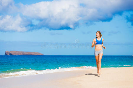 在海滩上跑步的美丽的运动女子