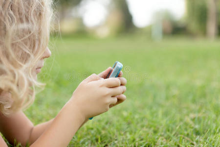 拿着手机躺在草地上的女孩