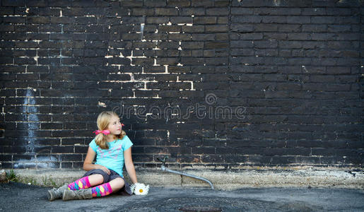 坐在砖墙旁边的地上的女孩