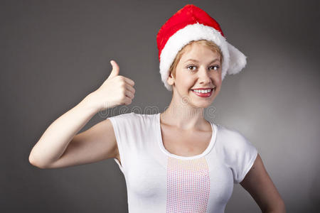 戴圣诞帽的快乐微笑女孩竖起大拇指