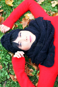 年轻的黑发女人在秋天的公园里放松
