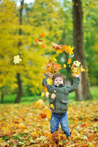 秋天公园里扔树叶的小男孩