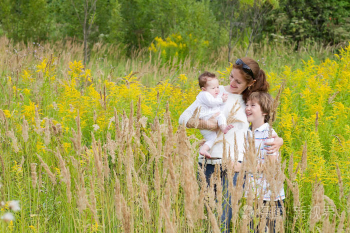 妈妈和孩子们快乐一位年轻的母亲带着两个孩子在黄花地里家庭一位年轻