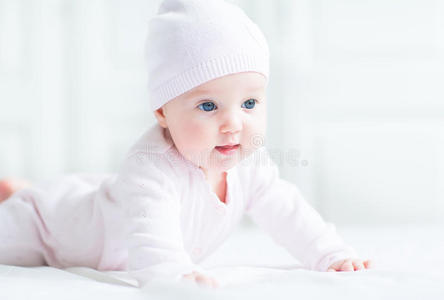 可爱的小女婴趴在肚子上，戴着针织帽