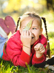 可爱的小女孩在公园里玩树叶