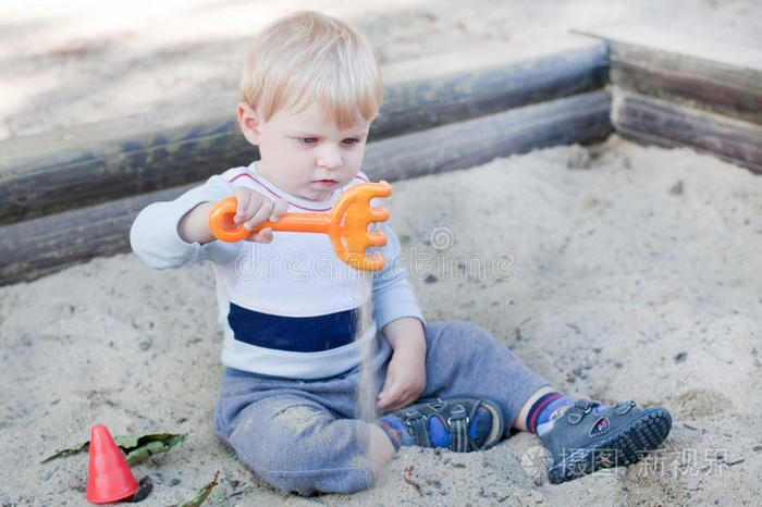 玩沙子和玩具的蹒跚学步的小男孩