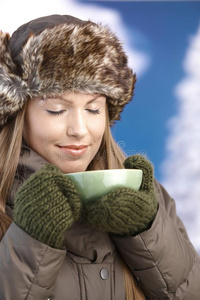 穿暖服享受热茶的年轻女性
