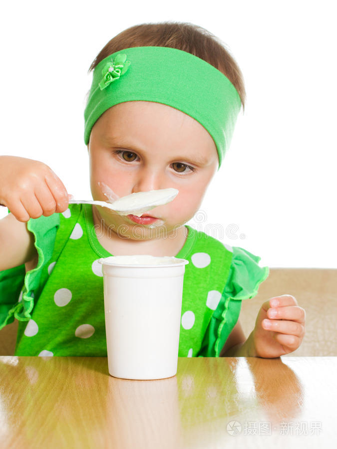 女孩用勺子吃乳制品。