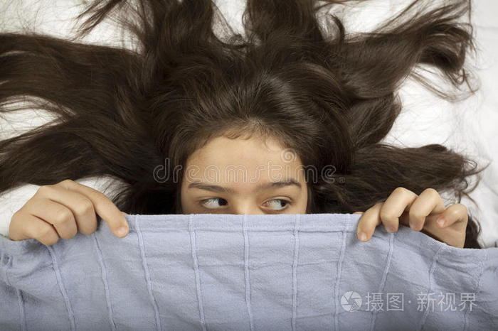 害怕的女孩躲在床上