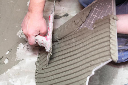 瓷砖胶铺贴建筑工人正在家里贴瓷砖地板胶照片