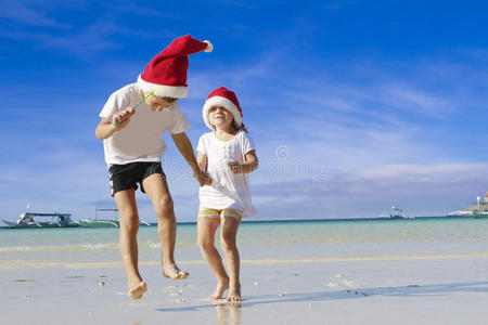 热带海滩上两个戴着圣诞帽的快乐小孩