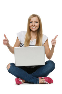 快乐的女人坐在笔记本电脑前竖起大拇指