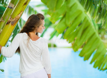 在热带棕榈树间放松的年轻女子