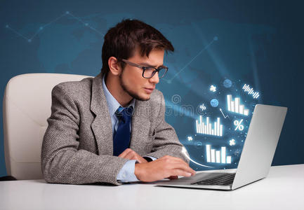 年轻人坐在办公桌旁,用笔记本电脑打字,上面有图表和照片