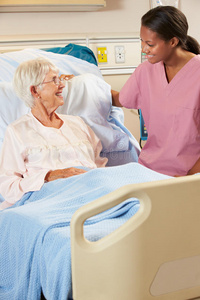 护士在病床上与高龄女病人交谈