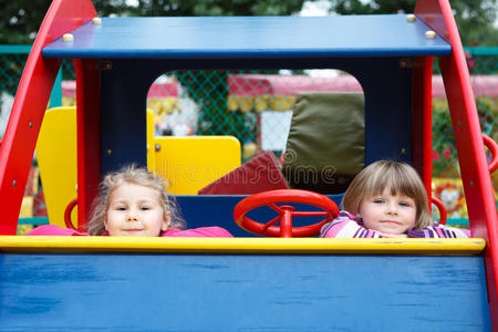两个快乐嬉戏的女孩坐在汽车玩具里