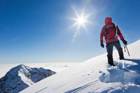 雪山悬崖登山者在一个阳光明媚的冬日到达雪山的山顶.照片