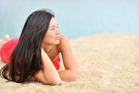 美丽的女人躺在沙滩上看著复制品