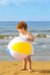 在沙滩上玩充气球的小女孩