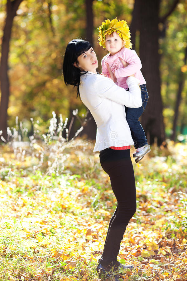 年轻的母亲把女儿抱在枫树花圈里照片-正版商用图片0mjz92-摄图新视界