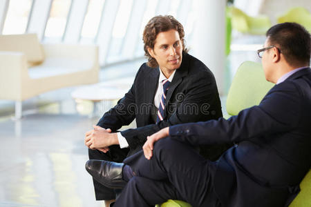 两个商人坐在现代办公室的沙发上