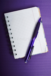 用铅笔在紫色波纹背景上书写的笔记本。