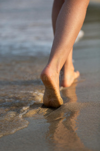 日落时海滩上美丽的女人的腿