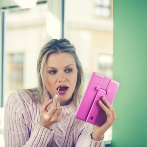 穿着粉红色毛衣的漂亮年轻女子戴着红色唇膏