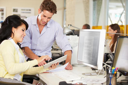 在繁忙的创意办公室使用数字平板电脑的员工照片