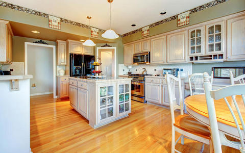 宽敞漂亮的白色厨房，硬木地板和绿色墙壁。