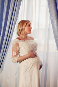 美丽的怀孕新娘靠窗摆姿势照片