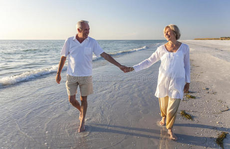 幸福的老年夫妇手牵手漫步热带海滩