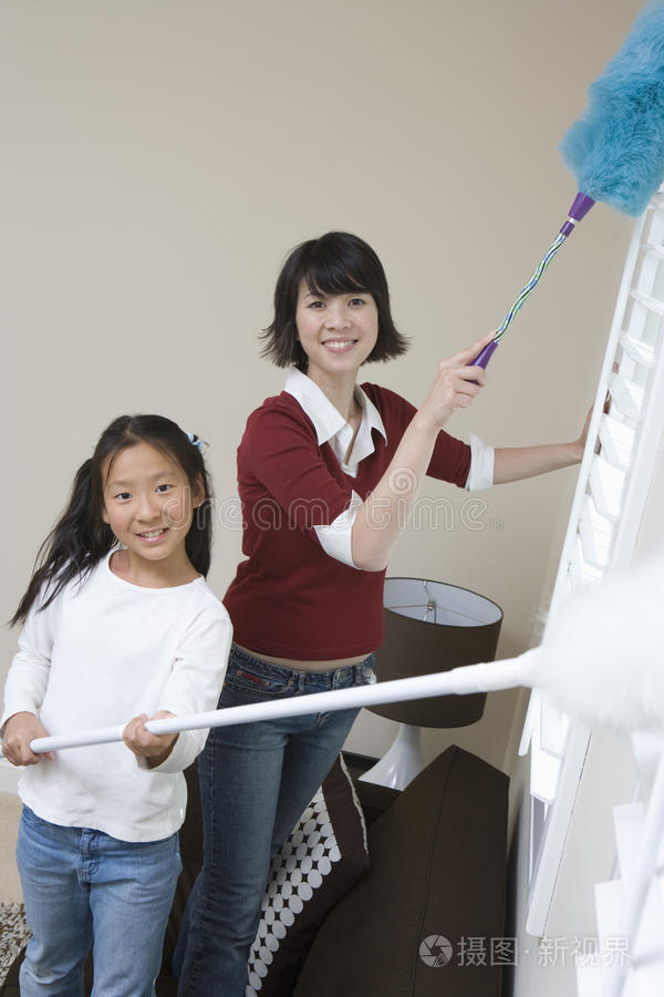 做家庭家务打扫房间的小女孩带着女儿的女人在洗衣机旁站在家里拖把