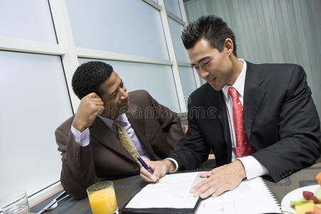 一个人看着他的商业伙伴签署文件