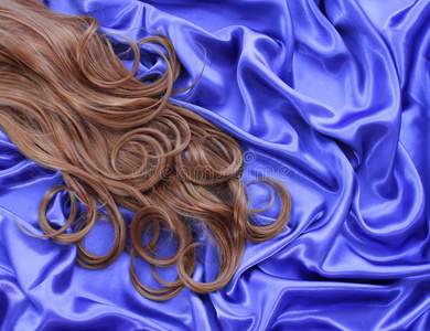 蓝色丝绸织物上卷曲的棕色头发