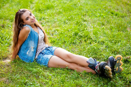 坐在草地上的穿旱冰鞋的女孩