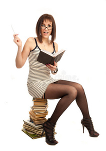 一个漂亮的女孩拿着一本书坐在一堆书上