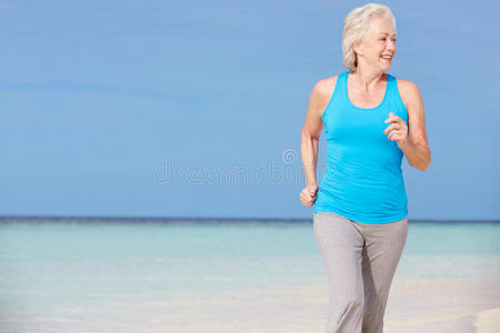 在美丽的海滩上奔跑的老妇人图片