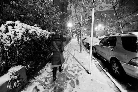 在一个冰天雪地的夜晚，一个孤独的女人走在被雪覆盖的哈莱姆街人行道上。