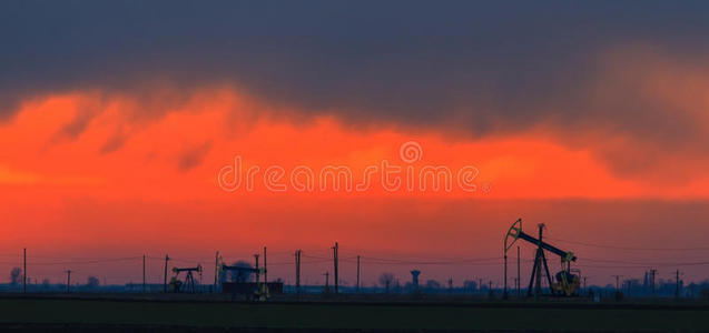 夕阳天空下的油泵和钻机油田图片