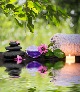 两支蜡烛和毛巾水上有黑色的石头和紫色的花