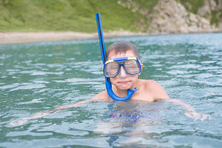 男孩戴着潜水面具在海里游泳。