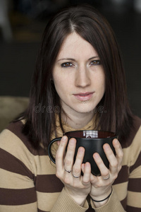 棕色头发和眼睛的年轻女人拿着黑色咖啡杯