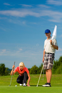 在球场上打高尔夫球的运动型年轻夫妇